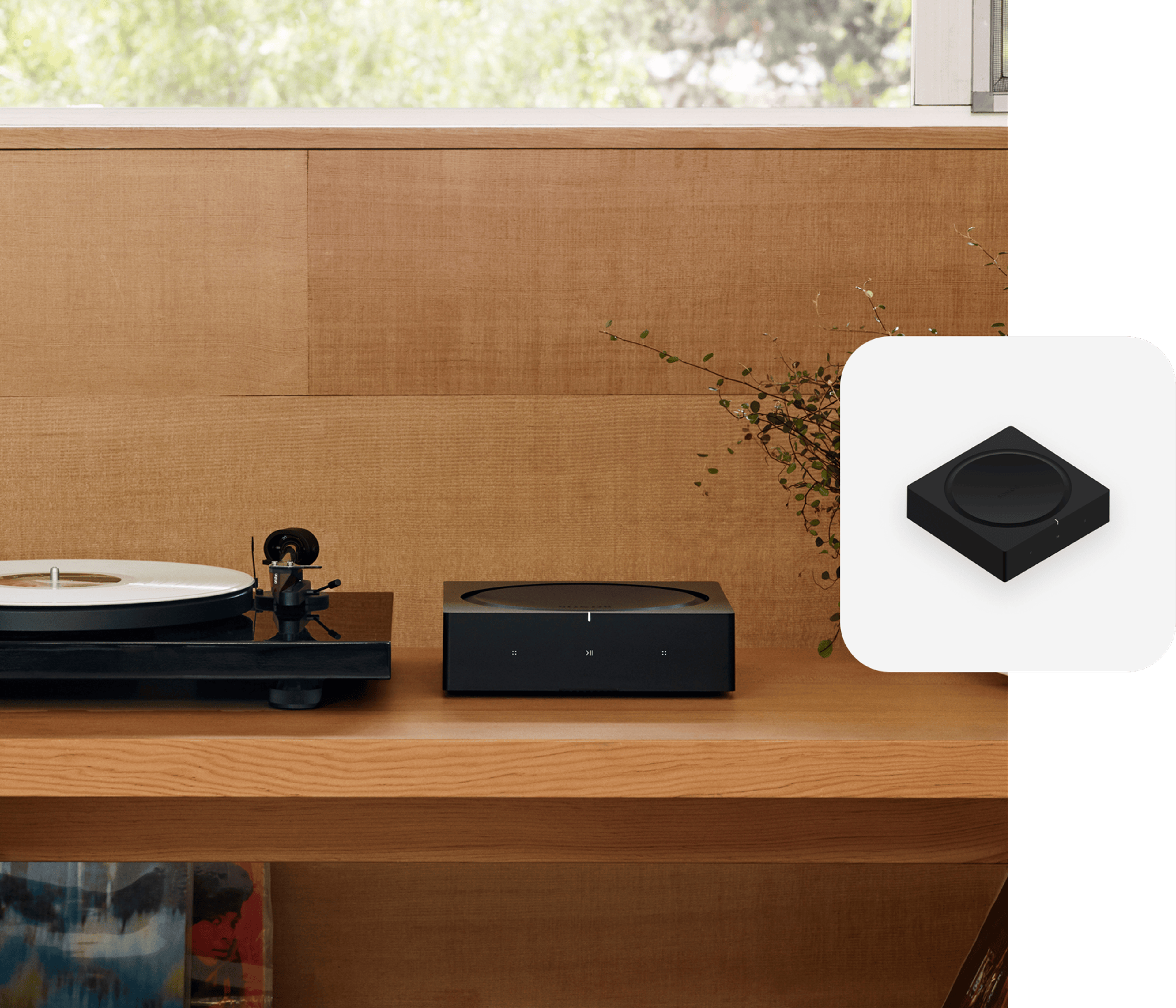 Un Sonos Amp sobre un estante junto a una tornamesa