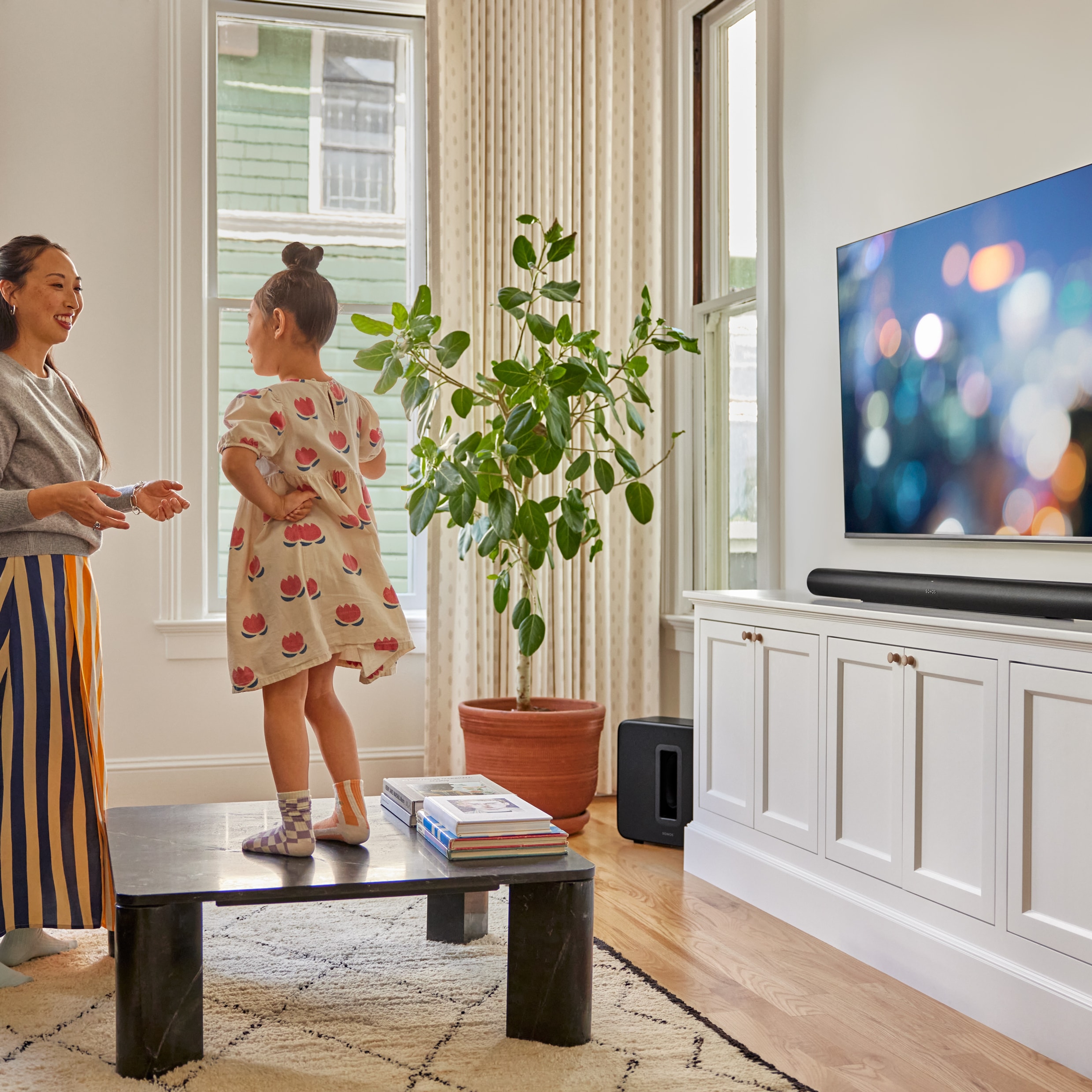 En mor og datter leker foran TV-en med en svart Arc Ultra