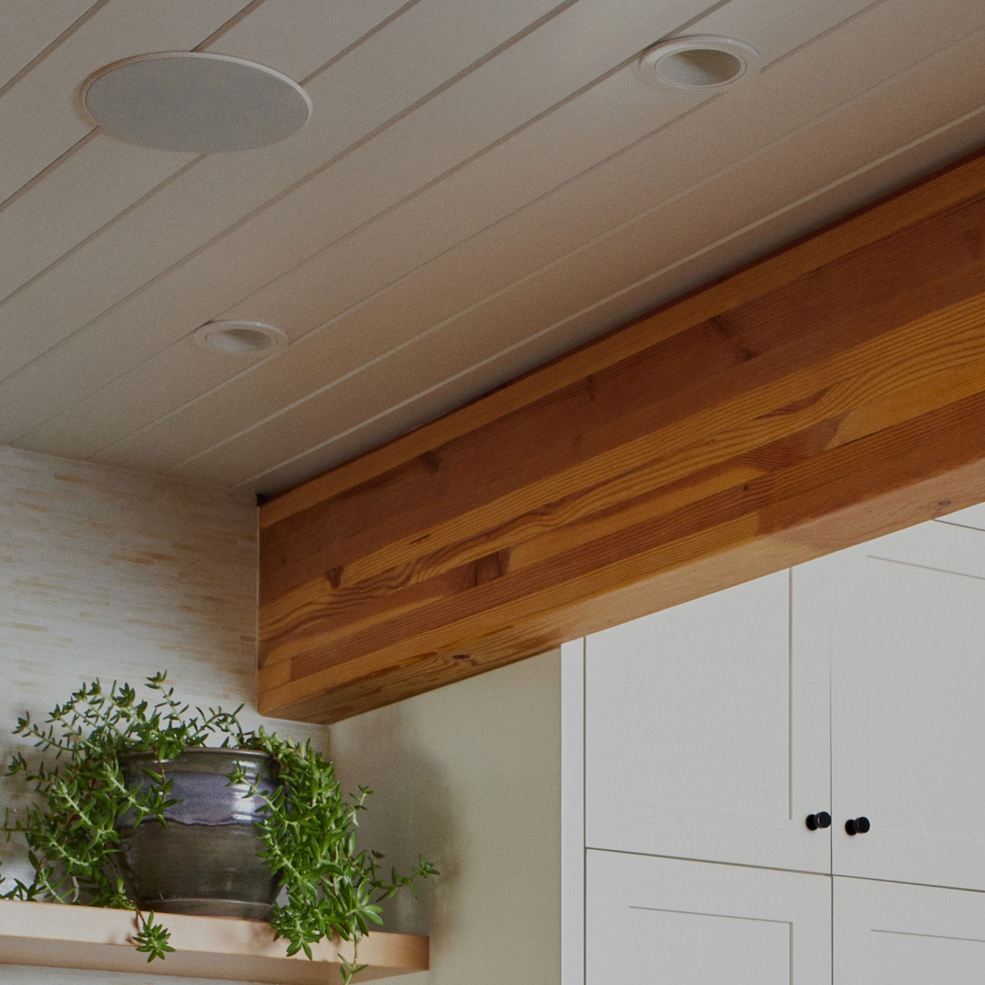 Nærbilde av In-Ceiling-høyttalere av Sonos og Sonance installert i taket over hyller
