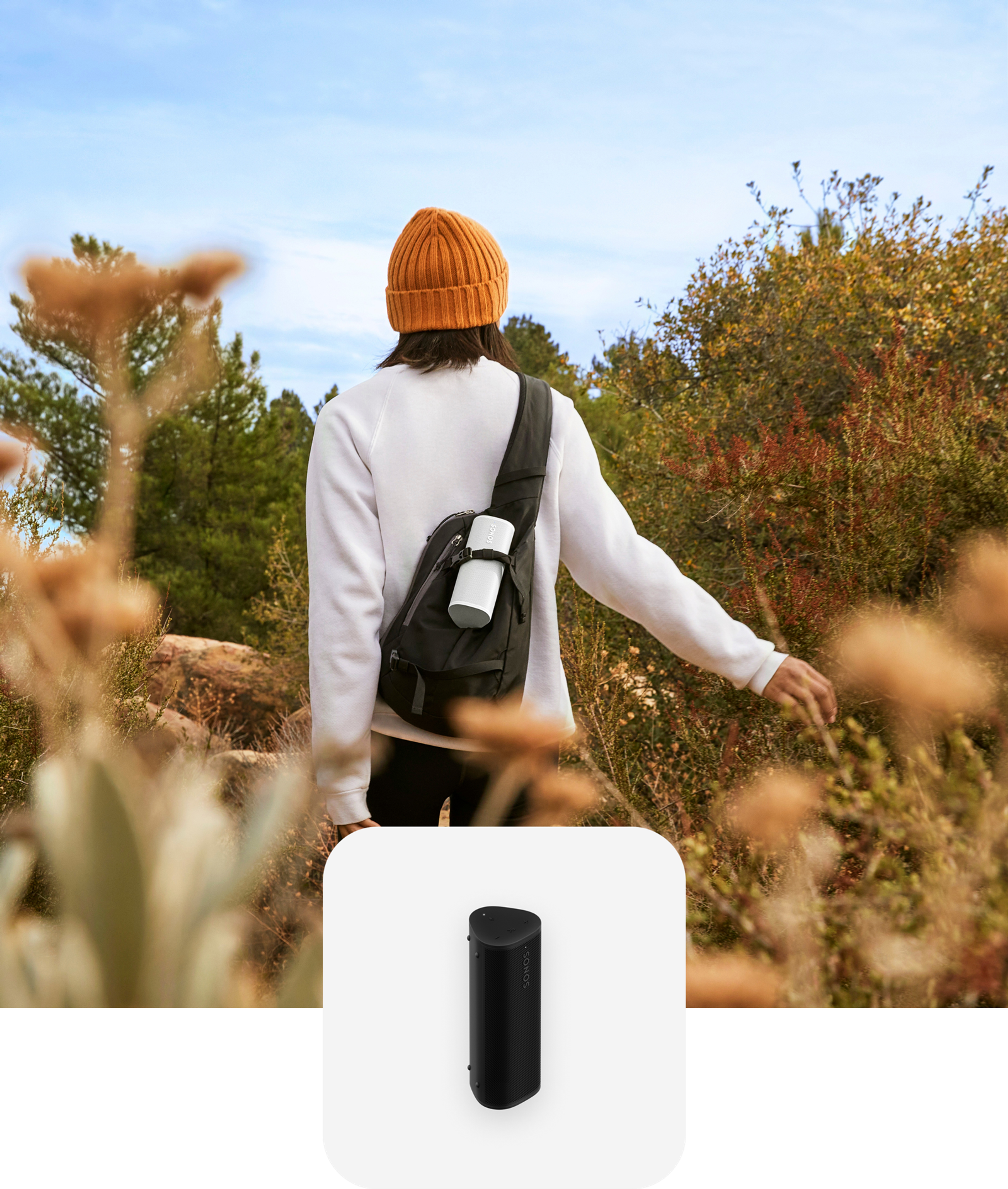 Un usuario practica senderismo mientras escucha una Roam 2 en color blanco que lleva en su mochila