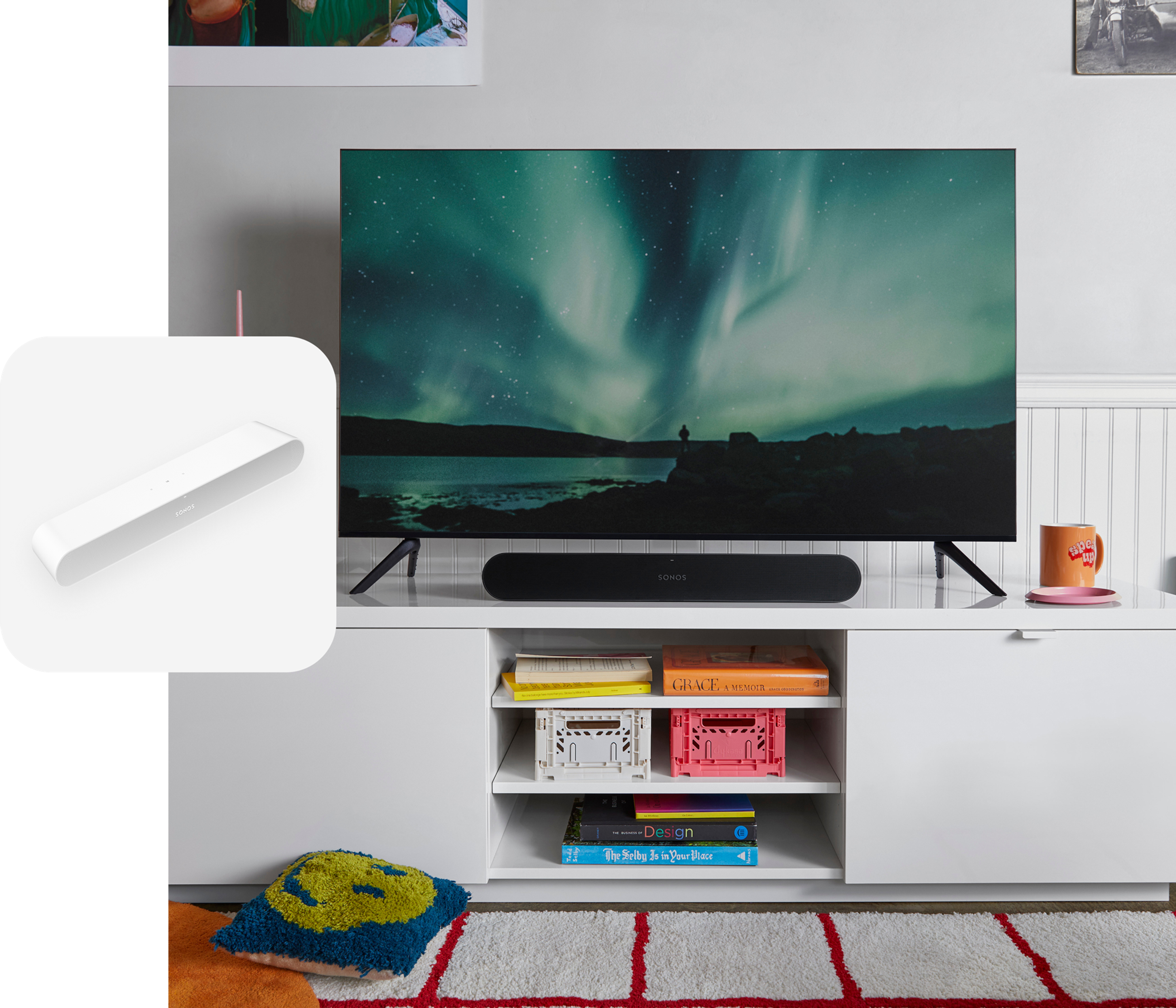 Una barra de sonido Sonos Ray en color negro debajo de una TV en un mueble blanco
