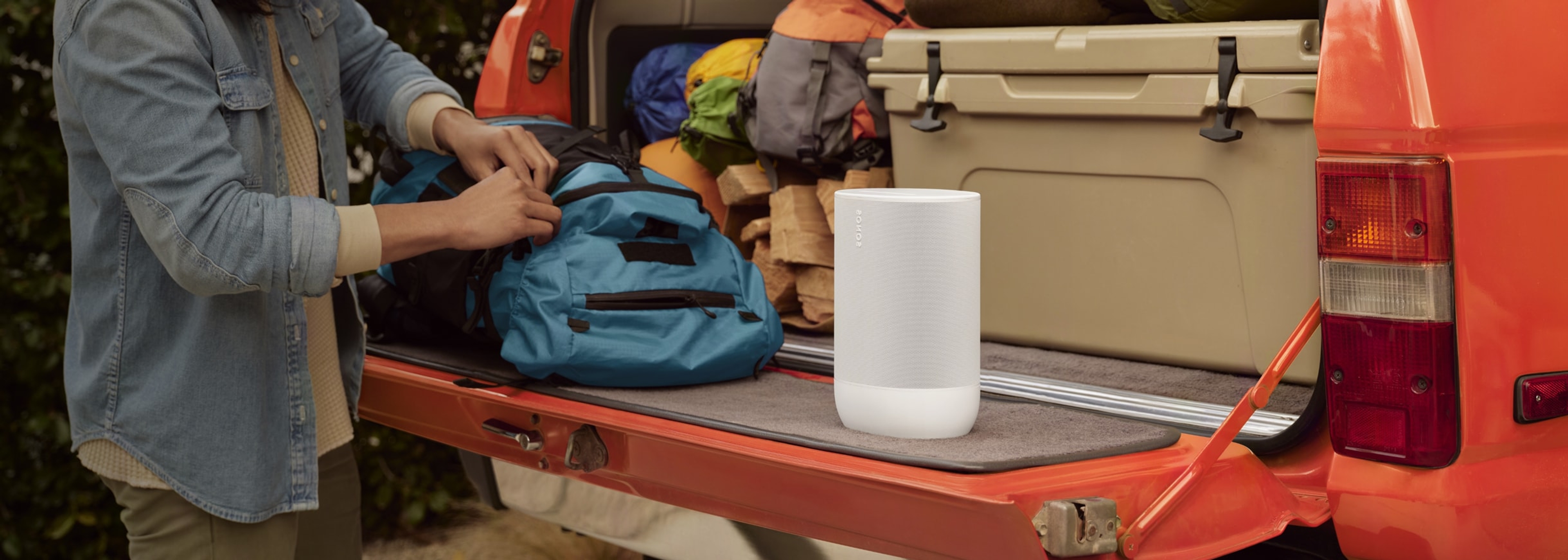 Una persona si prepara per andare in campeggio e porta con sé uno speaker portatile Move 2 bianco