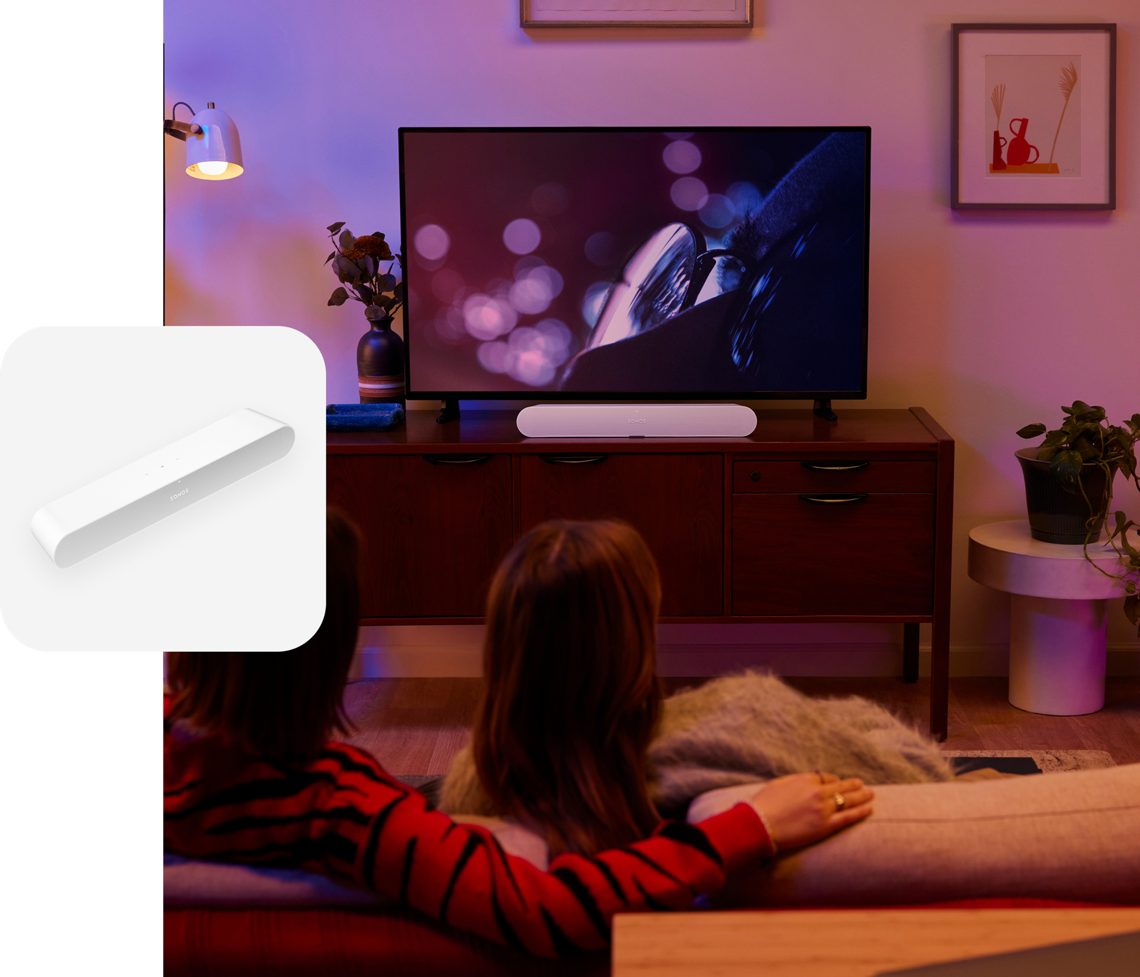 Una pareja mira una película en el sillón de la sala con el sonido de una barra de sonido Sonos Ray en color blanco