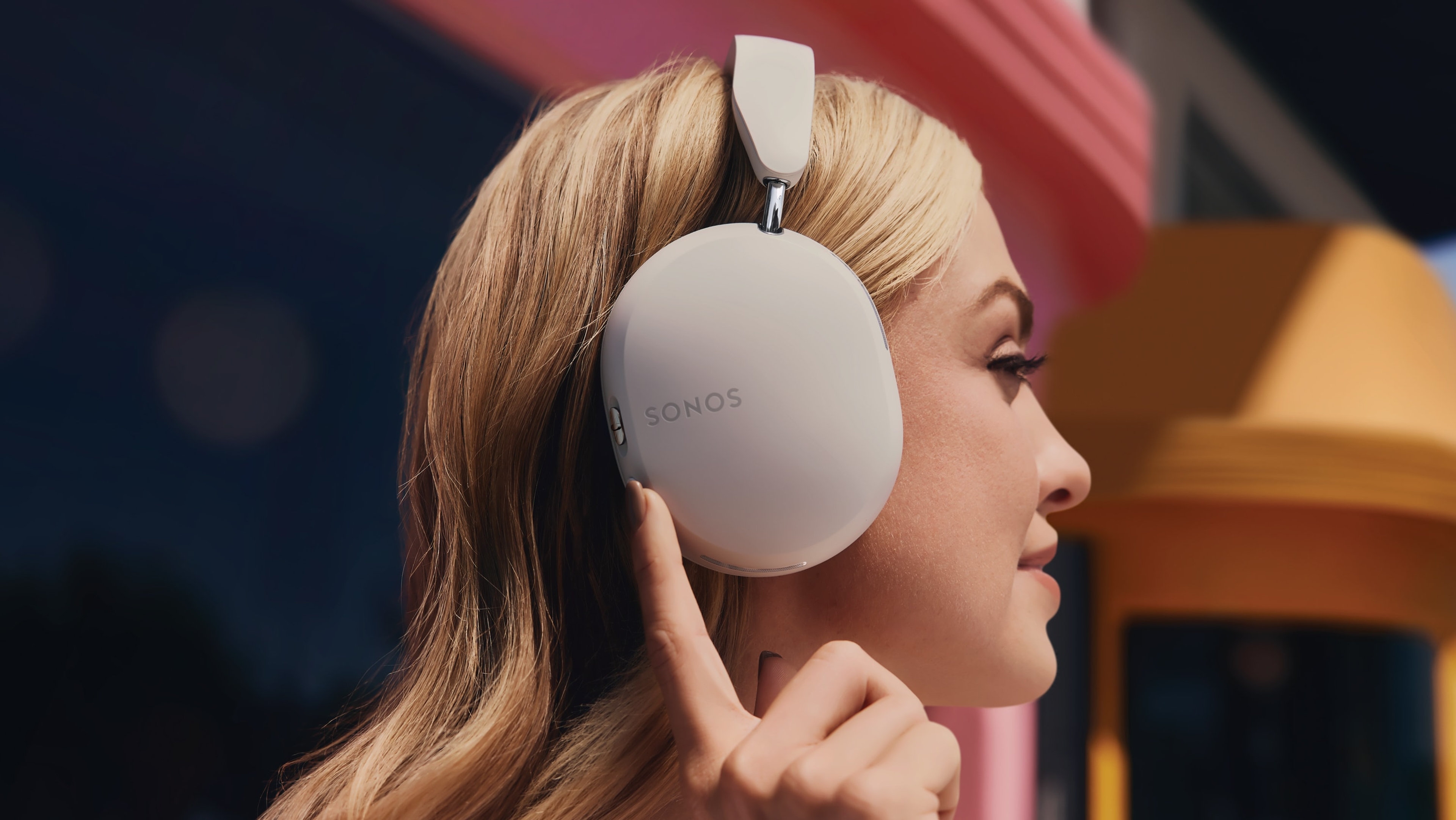 Profil d'une personne portant un casque Sonos Ace en Soft White et appuyant sur le bouton de réduction active du bruit