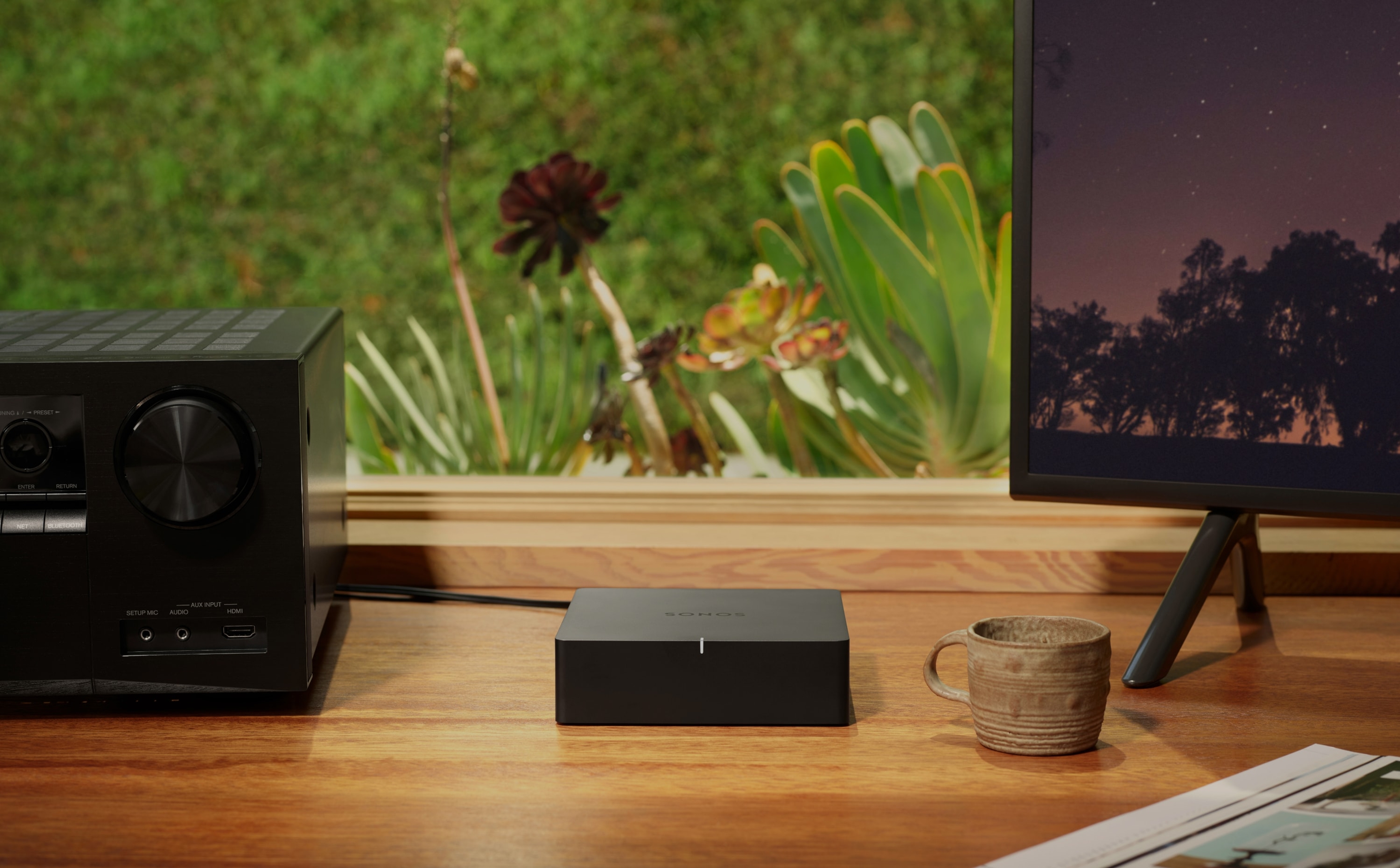 机の上のステレオレシーバーの隣にあるSonos Port